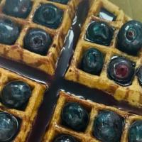The Blue Drip Waffles · One vegan  blueberry waffle covered with blueberries and blueberry syrup.