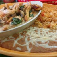 Pollo Adobe · Grilled chicken breast topped with a creamy cheese sauce and spinach, served with rice, bean...