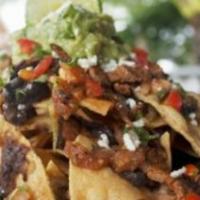 Nachos De La Casa · Cheese nachos with assorted toppings of seasoned ground beef, shredded chicken and beans, co...