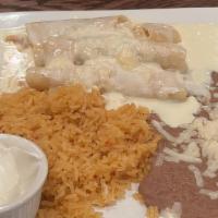 Enchiladas De Pollo · Three corn tortillas filled with shredded chicken topped with cheese sauce. Served with rice...