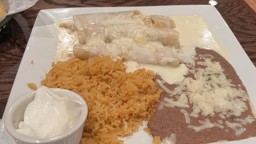 Enchiladas De Pollo · Three corn tortillas filled with shredded chicken topped with cheese sauce. Served with rice, beans and a side of sour cream.