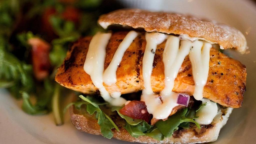 Grilled Salmon Sandwich · Grilled salmon brushed with dill butter and served on a whole wheat bun with arugula, red onion, tomato, and lemon basil mayo.