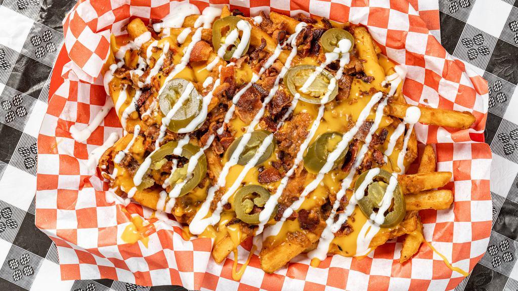 Junkyard Fry · Seasoned Fries covered with warm Nacho Cheese, Chili, Crispy Bacon Pieces, Jalapeño and topped with Ranch Dressing.