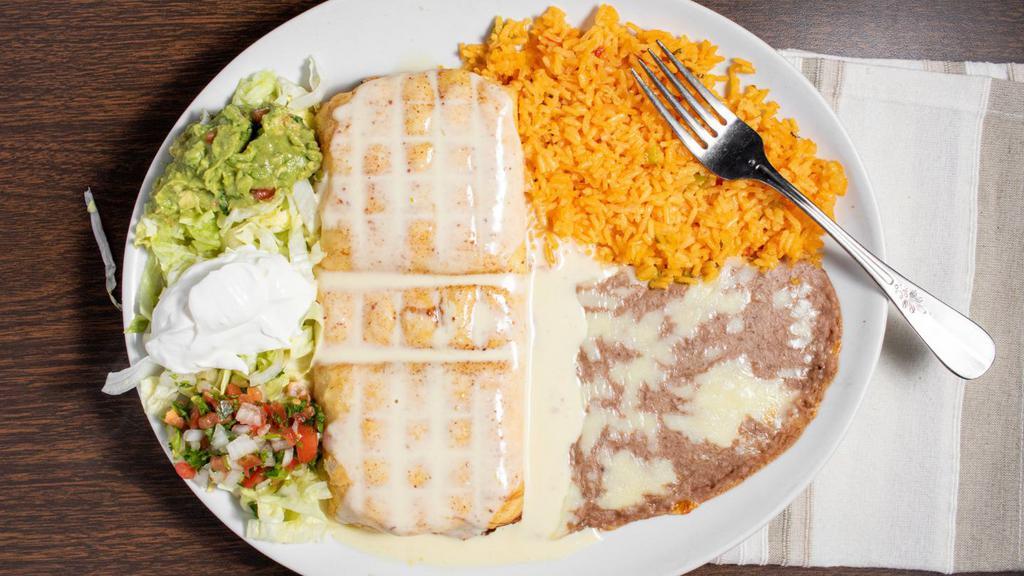 Chimichanga · Deep fried tortilla stuffed with beef or chicken topped with cheese sauce, served with rice, beans and salad.