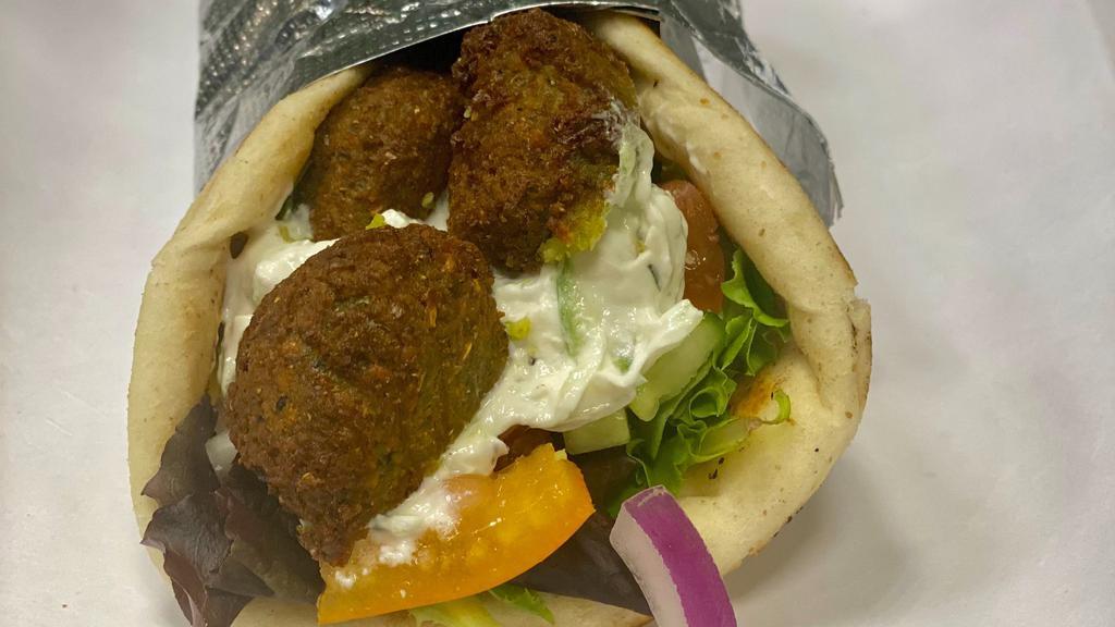 Falafel Sandwich · Served in a warm pita with spring mix lettuce, tomatoes, cucumbers, red  onions &  choice of tzatziki sauce or hummus