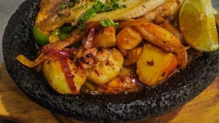Molcajete De Mariscos · Grilled  fish,  shrimp  with  head  and  no  head,  clams  and  mini  scallops,  seasoned  with butter, lemon sauce, corn on the cob and   white   rice.   served   with   lettuce,   onions,  orange,  cucumber,  tomato  and  avocado.