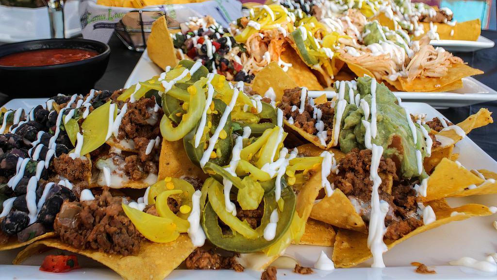 Grave Digger Nachos · Your choice of one protein, bread and butter jalapeños and onions, sour cream, guacamole, and black bean salsa. Topped with queso dip.