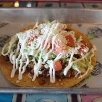 Tostada · Flat crunchy tortilla with your protein choice, refried beans, lettuce, tomatoes, sour cream...