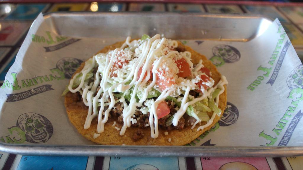 Tostada · Flat crunchy tortilla with your protein choice, refried beans, lettuce, tomatoes, sour cream and queso fresco