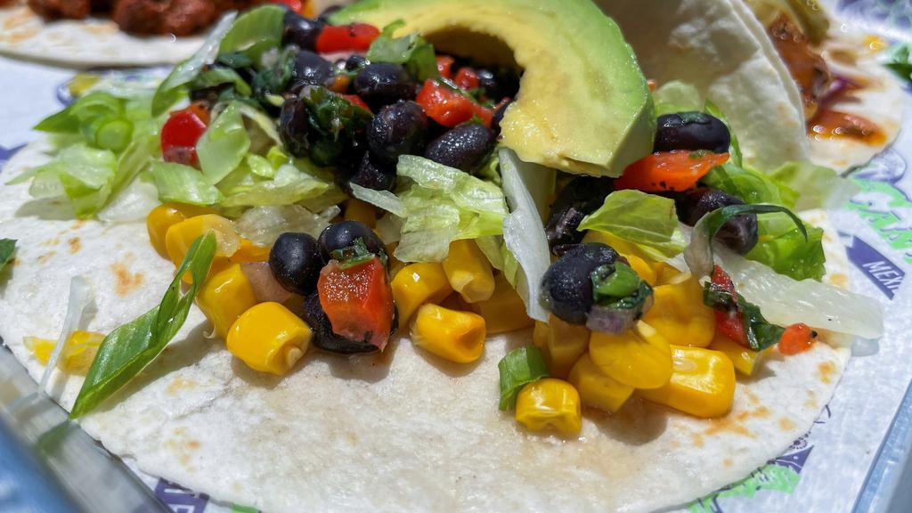 Veggie Taco · Lettuce, white rice vegetable medley, black bean salsa, corn, fresh lime pico de gallo, and a slice of avocado. This taco is served cold.