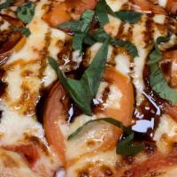 The Caprese Pizza · Sliced Roma tomatoes, mozzarella, over red sauce and fin dished with balsamic glaze and fres...