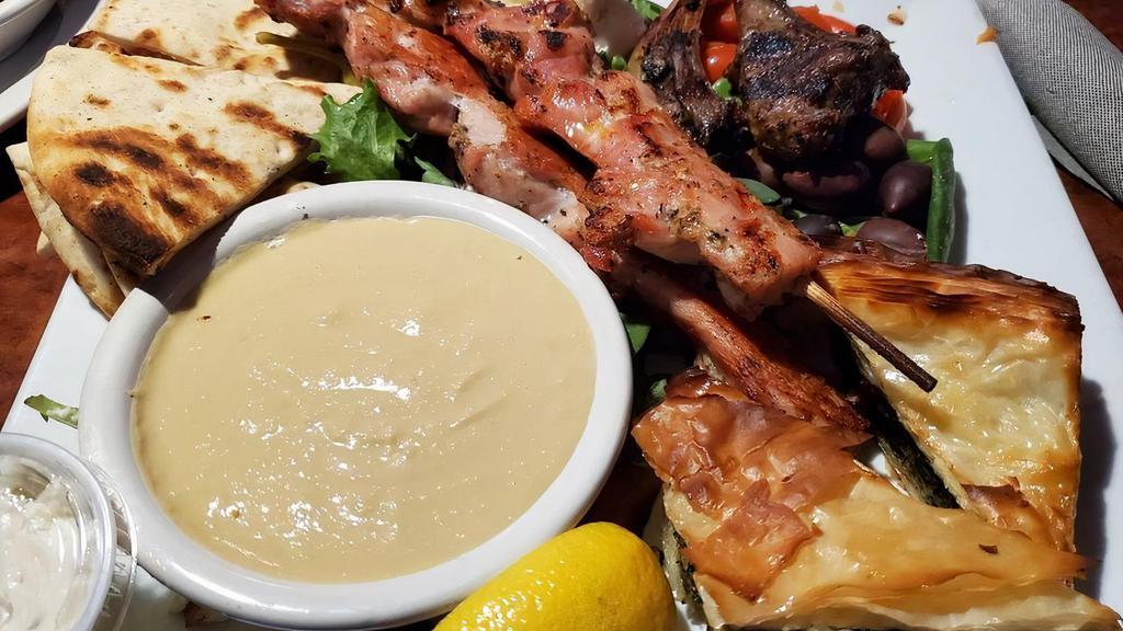 Greek Sampler Platter · Two colorado raised lamb chops, two chicken skewers, hummus & pita bread. Garnished with feta cheese & olives.