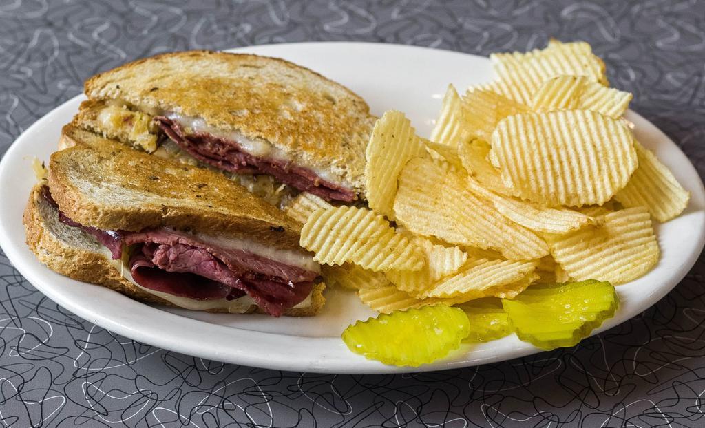 Grilled Corned Beef Rueben Sandwich · Traditional New York style - leaned corned beef, Swiss cheese and kraut on light rye bread, with pickles on the side.