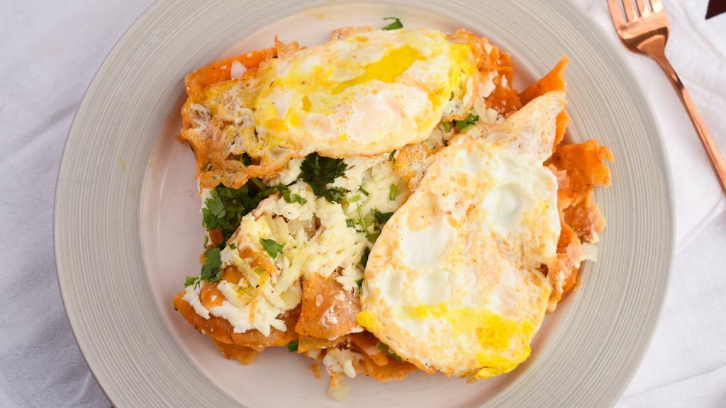 Breakfast Nachos – Chilaquiles · Corn tortilla chips with red salsa, beans, cheese, onions, cilantro, Mexican crema topped with two sunny-side-up eggs.