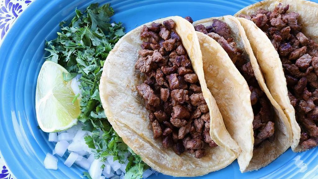 Tacos Carne Asada Meal · Three corn tortillas stuffed with sliced steak. Comes with a side of onions, cilantro, lime, and a side order of refried beans.