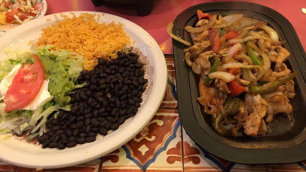 Fajitas · Your choice of steak or chicken strips marinated in secret sauce then delivered sizzling hot over a bed of sautéedonions, tomatoes, green peppers, and red peppers. Served with salsa Mexicana sour cream, guacamole, rice, beans, and your choice of flour or corn tortilla.