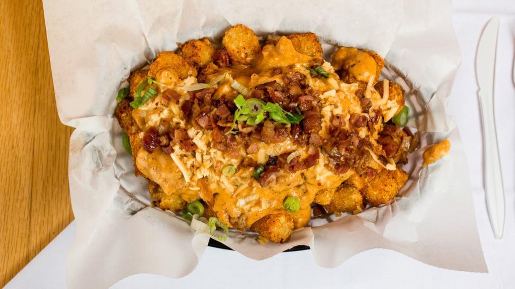 Mojo Tots · Seasoned Tots smothered in our homemade bacon chorizo Spanish sausage gravy topped with smoked gouda and crumbled candied bacon.