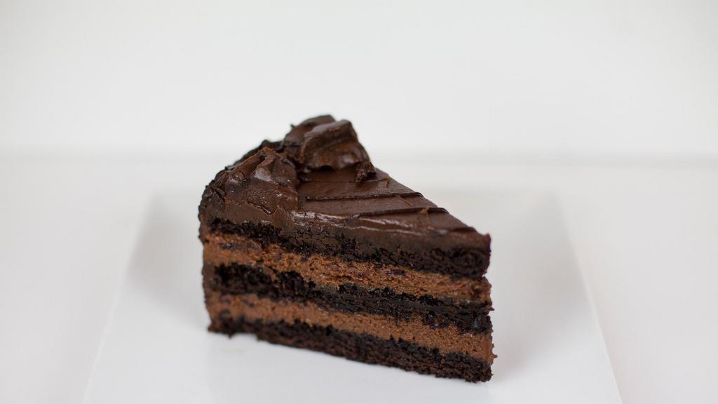 Chocolate Layer Mousse Cake · A true delight for all chocolate lovers! Three delicious layers of moist chocolate cake separated by layers of decadent chocolate mousse with a generous portion of smooth milk chocolate icing on the top and sides, topped off with chocolate chips and drizzled with ganache.