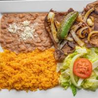 Carne Asada* · Grilled steak topped with grilled onions. Served with rice, refried beans and salad. Consumi...