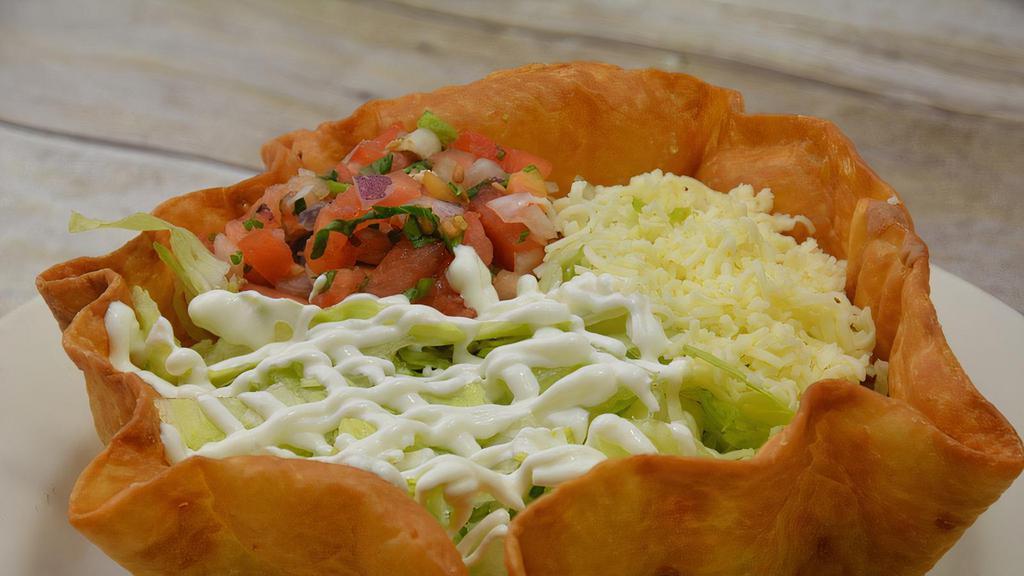 Taco Salad · A fried tortilla shaped like a bowl, filled with choice of ground beef or shredded chicken and topped with lettuce, sliced tomatoes, sour cream, and shredded cheese.