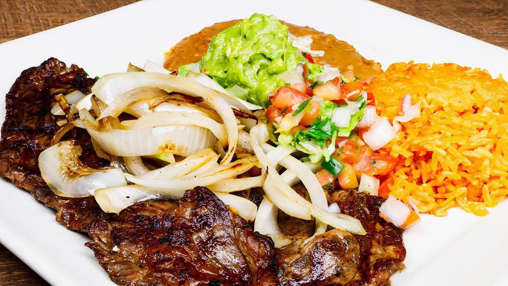 Carne Asada · Rib-eye steak with refried beans with cheese, guacamole salsa, and tortillas.