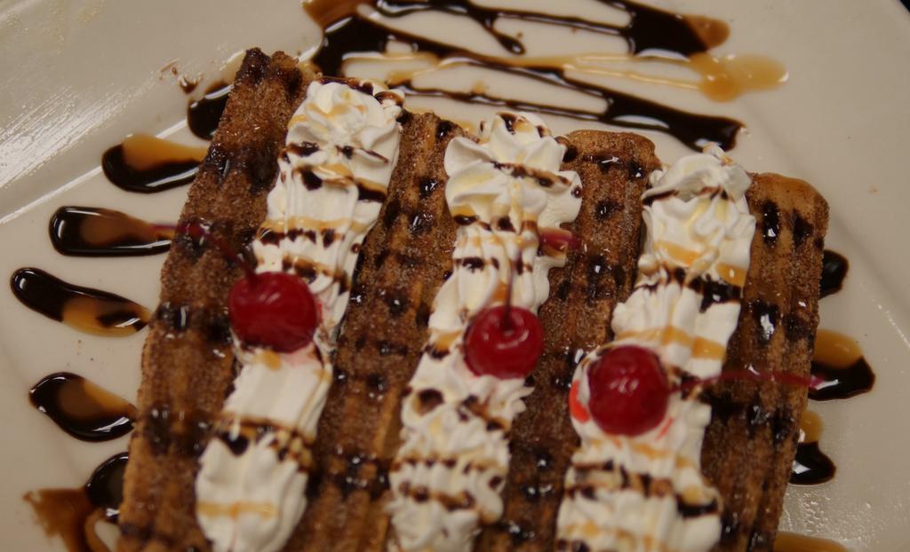 Churros · Fried dough sticks covered in cinnamon and sugar, topped with whipped cream, strawberry, and chocolate syrup.