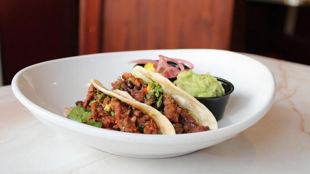Meatless Tacos · Two bbq Beyond Meat tacos, guacamole, pickled ginger, black bean salsa, cilantro, flour tortillas, pickled onions and banana peppers.