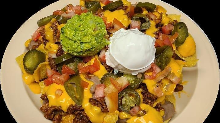 Nachos · chips topped with the meat of your choice, jalapeños, beans, yellow cheese, tomatoes, guacamole, and sour cream