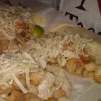 Fish Tacos · Three grilled or fried fish tacos topped with creamy cancum sauce,cheese and shredded cabbage.