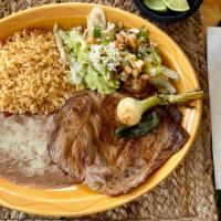Carne Asada · Steak with refried beans, guacamole salad, flour tortillas, and Spanish rice.