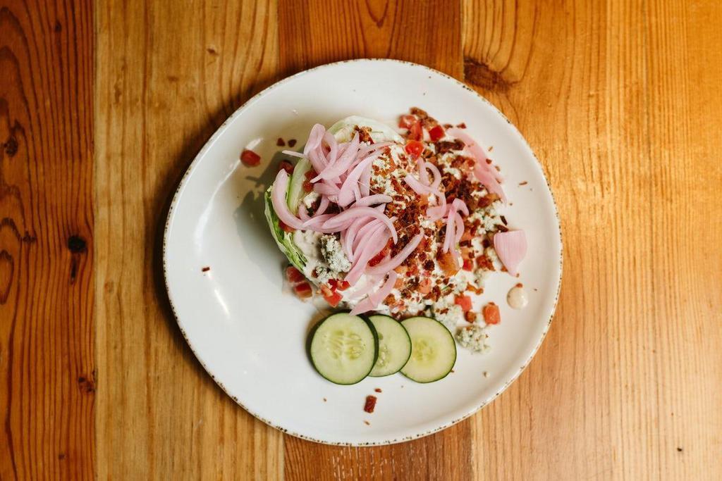 Wedge Salad · Iceberg wedge, tomatoes, cucumbers, pickled red onions, bacon, and Bleu cheese crumbles served with creamy Bleu cheese dressing.