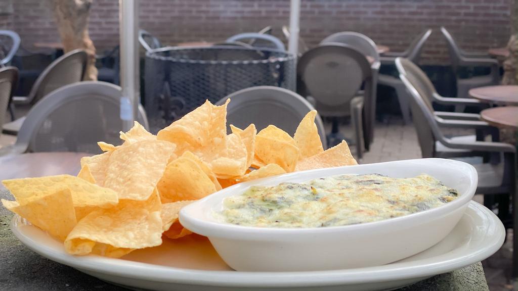Spinach Artichoke Dip · Our classic creamy spinach and artichoke dip topped with melted monterey jack cheese and served with crispy tortilla chips.