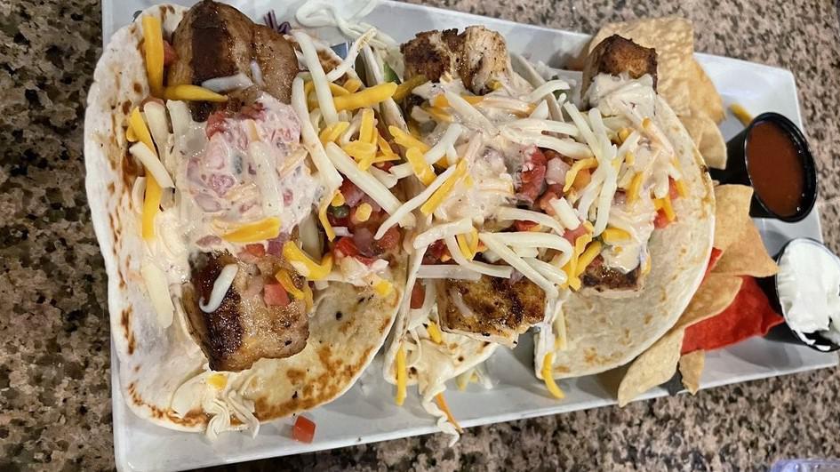 Baja Fish Tacos · Three soft shell tacos | Mahi Mahi | avocado | lettuce | pico de gallo | cheese | spicy ranch.