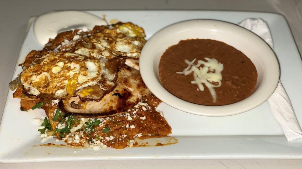 Chilaquiles · Deep fried corn tortillas cover with red or green sauce served with cilantro, onions, cheese, sour cream, and beans with your optional choice (chicken or steak) and two fried eggs.