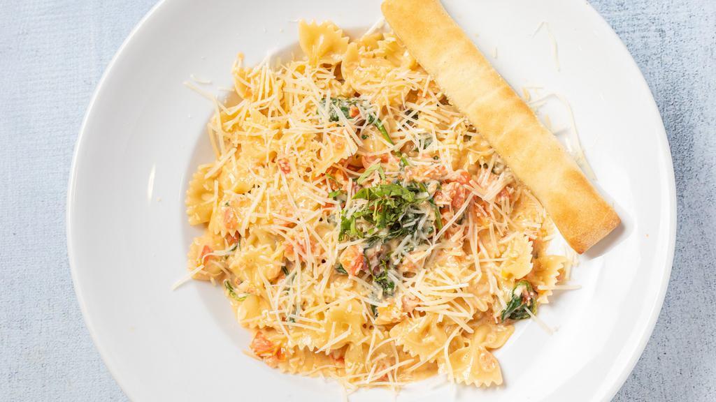 Pomodoro · Farfalle pasta and ripe Roma tomatoes meet a delightfully creamy wine-garlic sauce accompanied by sautéed spinach and basil. Garnished with Parmesan cheese.