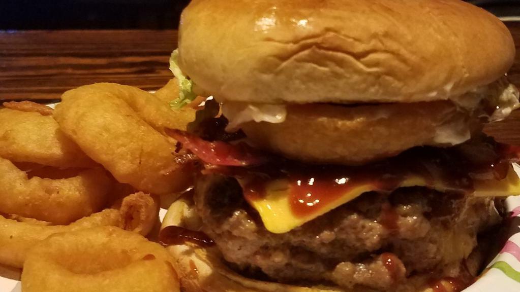 Signature Rodeo Burger · 100% seasoned ground beef topped with lettuce cheese tomatoes pickles BBQ sauce and {1} onion ring
