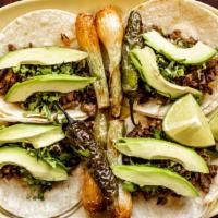 Tacos Caminos · Four grilled onion and steak tacos with bean smeared handmade tortillas served with onions a...