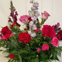 Mix Flower Bqt · A mix of red, pink, and purple flowers with green fillers in a clear glass vase.