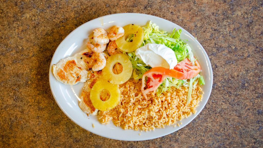 Pollo Real · Seasoned grilled chicken breast topped with sautéed shrimp, and pineapple, served with rice, lettuce, sour cream, and tomato.
