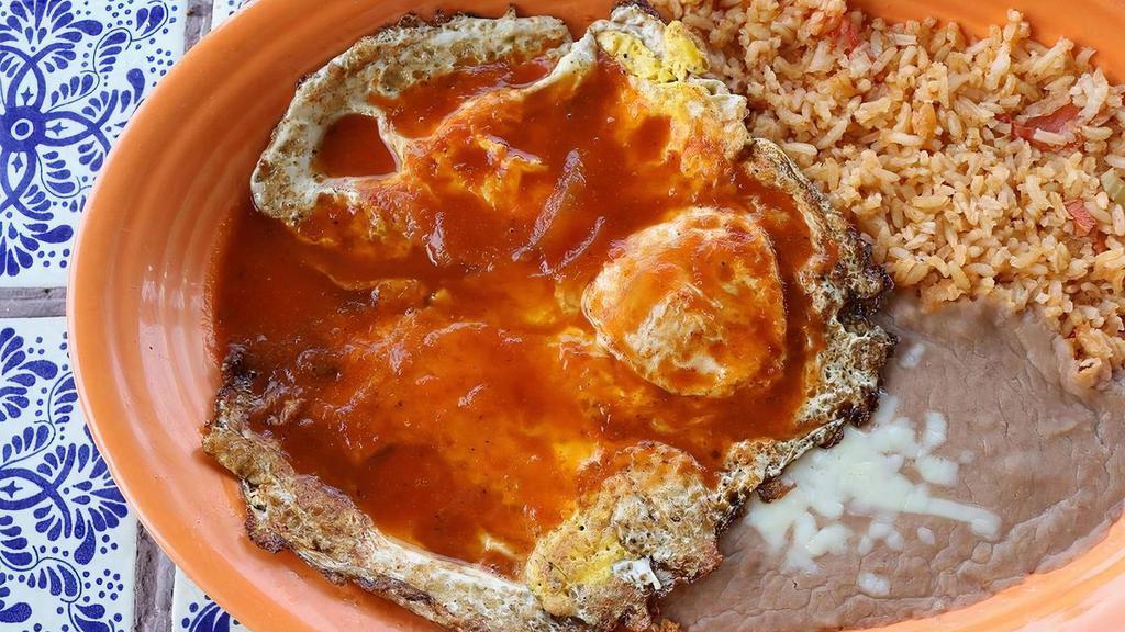 Huevos Rancheros · A traditional Mexican dish of over easy eggs topped with a savory red sauce, served with fresh rice, homemade refried beans, and your choice of corn or flour tortillas.