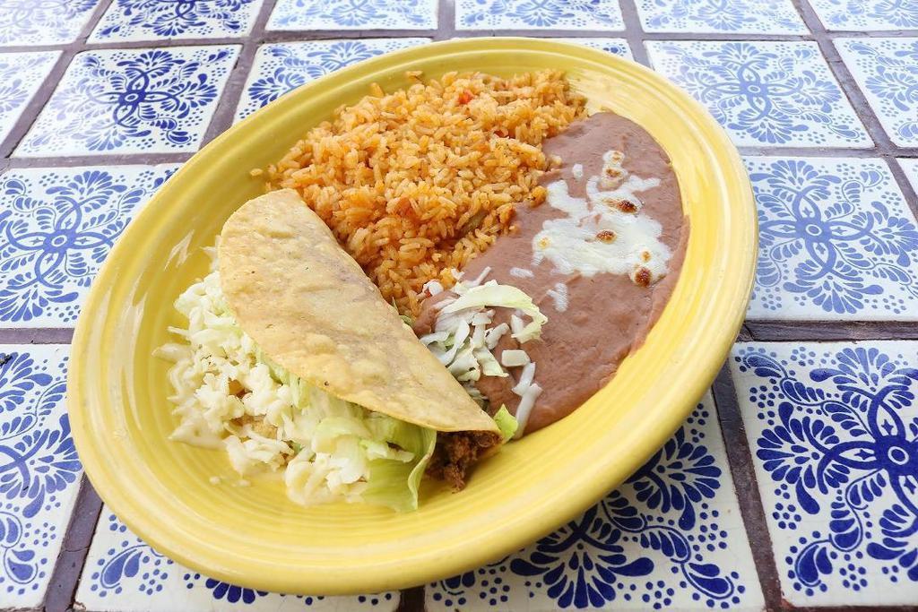 Lunch Taco · A crunchy or soft taco shell filled with your choice of ground beef or shredded chicken, topped with lettuce and cheese and served with a side of fresh rice and homemade refried beans.