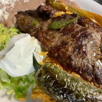 Carne Asada/Grill Steak · Tenderly grilled ribeye steak thin slice and served with rice, refried pinto beans, fresh gu...