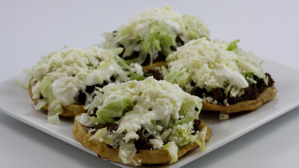 Sopes (3) · Three fried homemade corn base patties. Served with your choice of meat and topped with refried pinto beans, lettuce, sour cream and queso fresco.