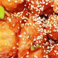 Sesame Chicken · Garlic, scallions and crispy chicken, with sweet and sour sauce. Garnished with steamed broc...