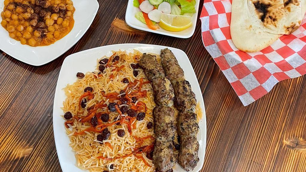 Afghan Beef Shami Kabab · Ground beef in an aromatic marinade of citrus, onion, and traditional Afghani seasoning, skewered and grilled and served with basmati rice, chickpeas, salad, sauce  and bread.