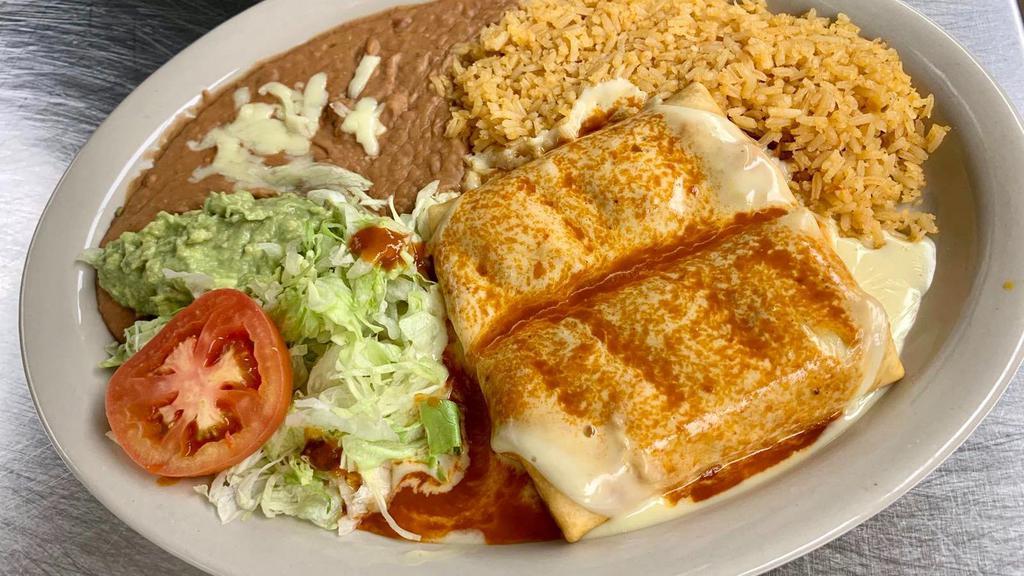 Chimichanga · (Soft or fried) Two flour tortillas filled with chicken or beef. Served with rice, beans, topped with white queso, red sauce, lettuce, sour cream, guacamole and tomato.