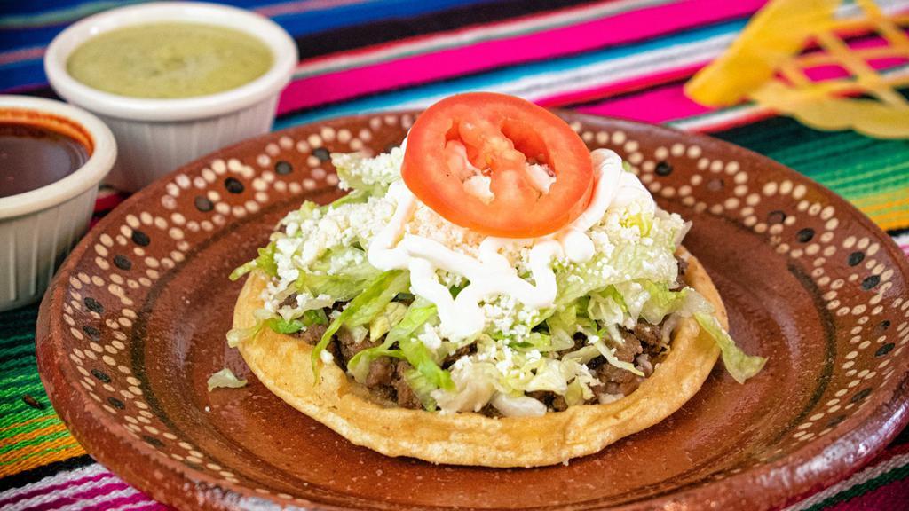 Sopes · Home made thick tortilla fried topped with beans, your choice of meat or veggie (from the guisados), lettuce, cheese, sour cream and a sliced tomatoe.