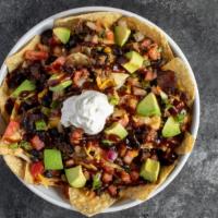 Brisket Nachos · A pile of tortilla chips is loaded with melted cheese, warm black beans and pulled smoke bri...