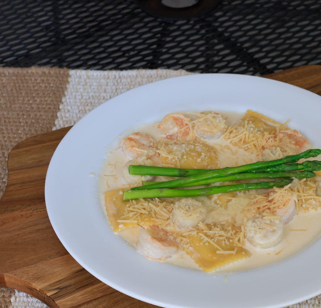 Lobster Ravioli · Lobster filled ravioli, tossed in sherry-lobster cream sauce. Accompanied by pan seared shrimp. Topped with asparagus and parmesan.