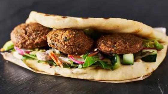 Falafel Wrap · Vegan. Three falafels, hummus, lettuce, tomatoes, red onions and tzatziki sauce in a pita wrap (gluten free available on request).